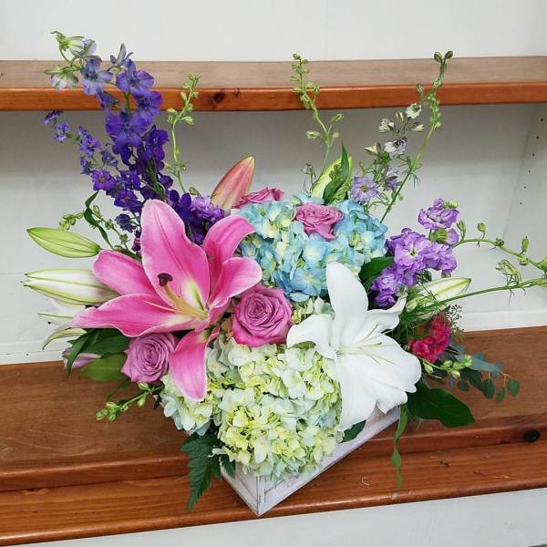Pink and white lilies with roses and hydrangeas in a white box