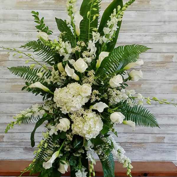 Tall white floral standing arrangement with calla lilies and roses