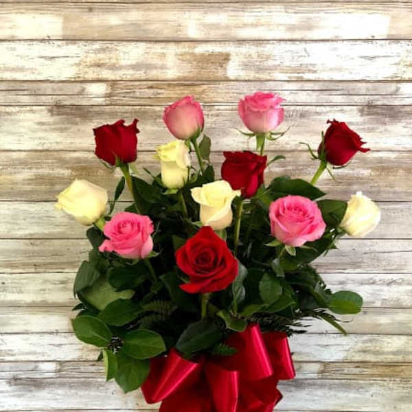 Bouquet of red, pink, and white roses with a red ribbon in a glass vase