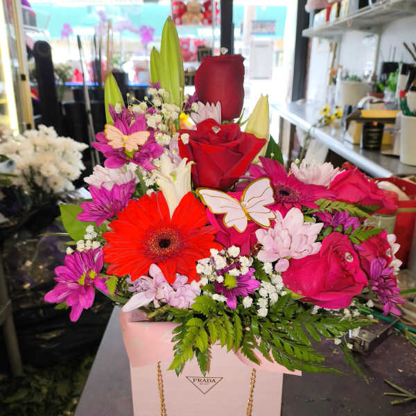 Bright mixed bouquet in a pink gift bag with roses and daisies