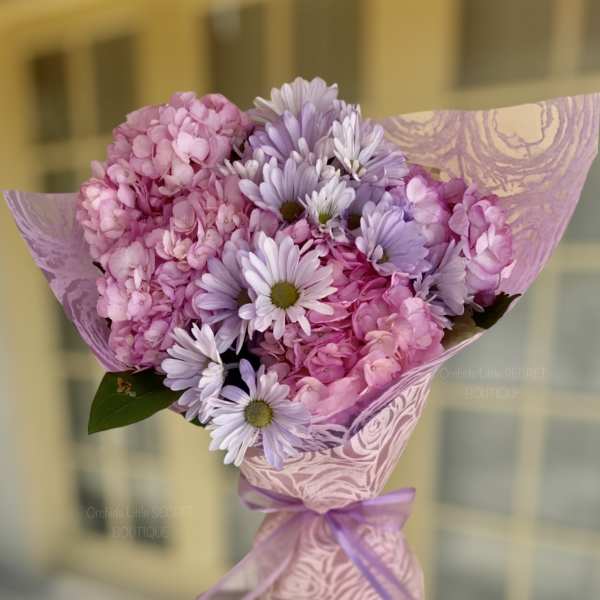 Pink and lavender bouquet wrapped in patterned paper with a ribbon