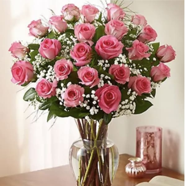 Pink roses arranged in a clear glass vase with white filler flowers