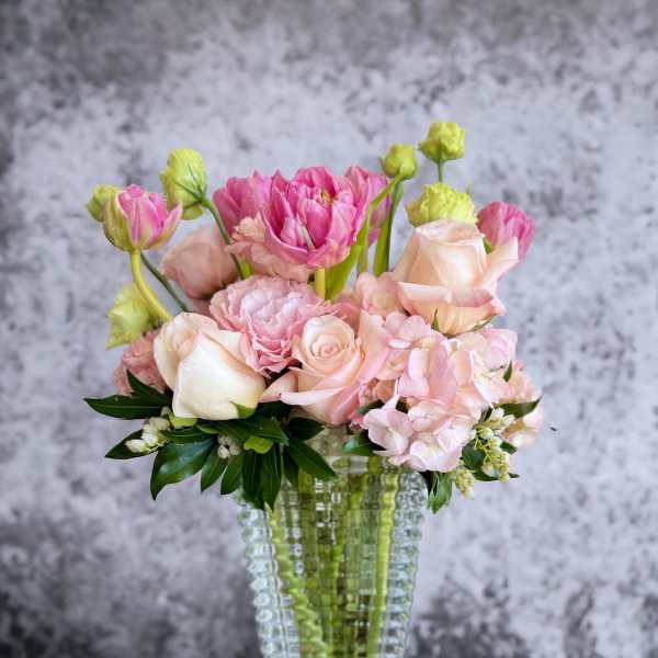 Pink and peach flowers arranged in a clear textured vase