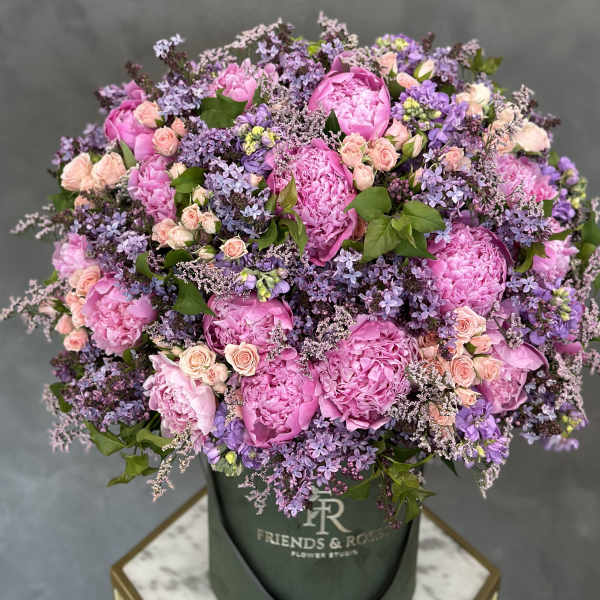 Pink peonies and lavender flowers in a dark green hat box
