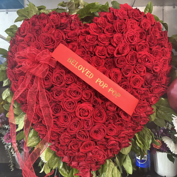 Heart-shaped bouquet of red roses with a ribbon and card