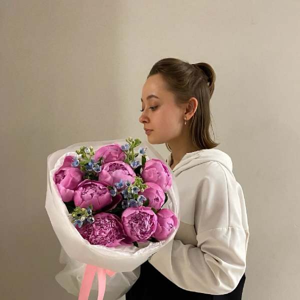 Woman holding a bouquet of pink peonies wrapped in white paper