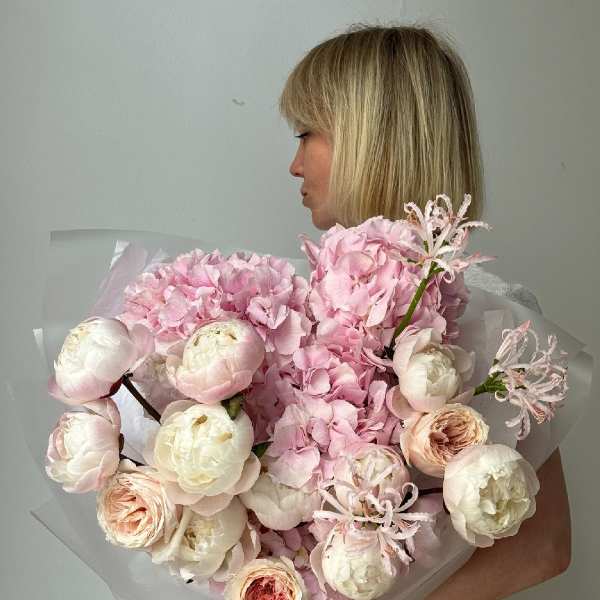 Woman holding a large bouquet of pale pink and white flowers