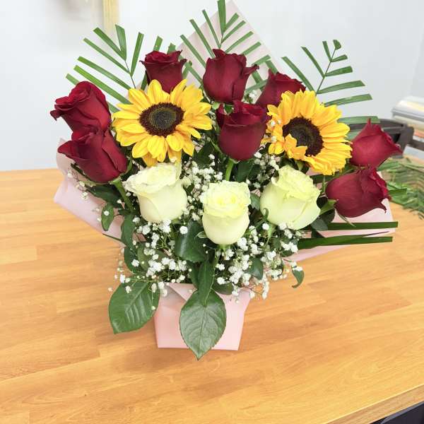 Bouquet of red and white roses with yellow sunflowers in a pink box