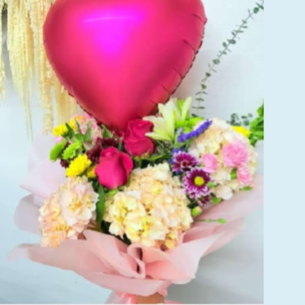 Pink heart balloon above a mixed bouquet of roses and pastel flowers