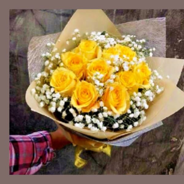Bouquet of yellow roses with white baby's breath in brown paper