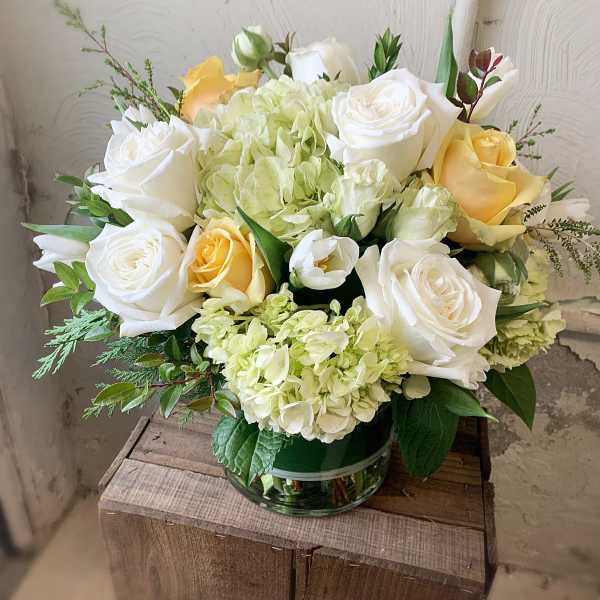 Bouquet of white and pale yellow roses with hydrangeas in a glass vase