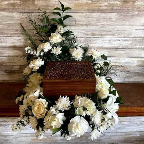 White floral casket spray arranged around a wooden casket