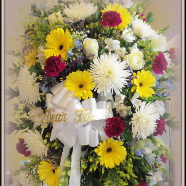 Large mixed flower standing spray with white ribbon and gold lettering