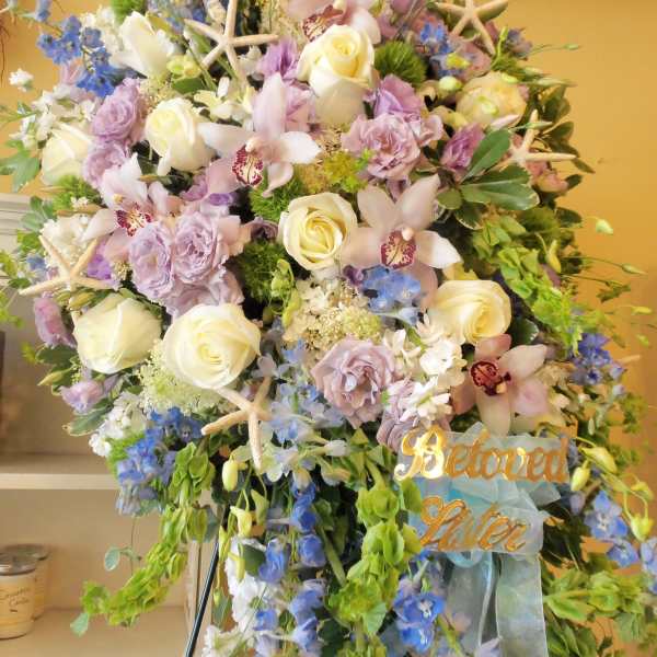 Large pastel floral standing spray with roses, orchids, and blue flowers