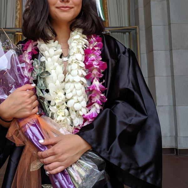 Graduate holding a bouquet of white and magenta orchids