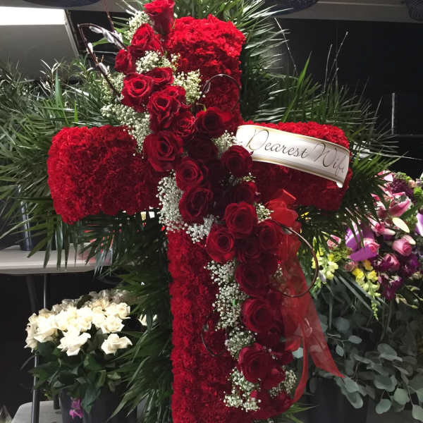 Red rose and carnation cross-shaped funeral spray with a ribbon