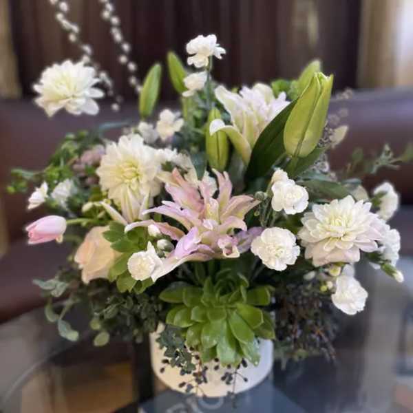 White and pale pink flowers arranged in a white vase