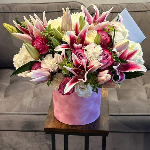 Bouquet of pink lilies and roses in a pink hatbox