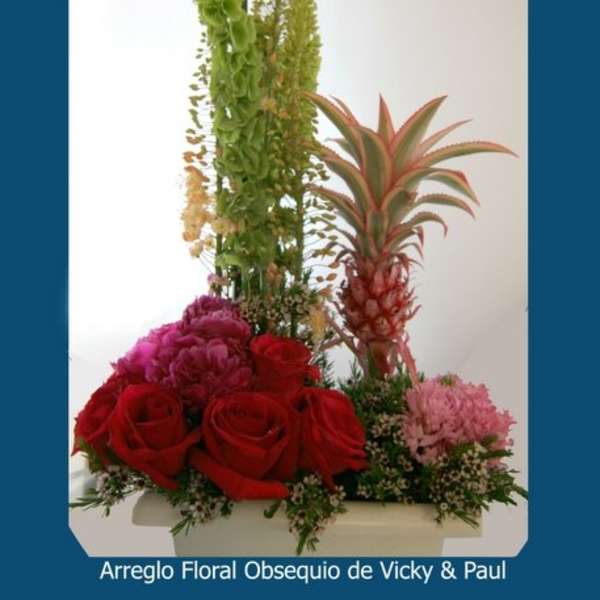 Tall tropical floral arrangement with red roses and a pineapple