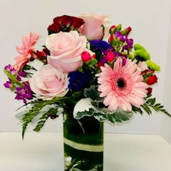 Mixed bouquet with pink roses and gerbera daisies in a glass vase