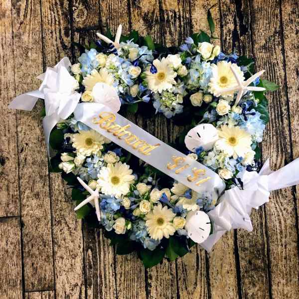 Heart-shaped floral wreath with white ribbon and pale blue flowers