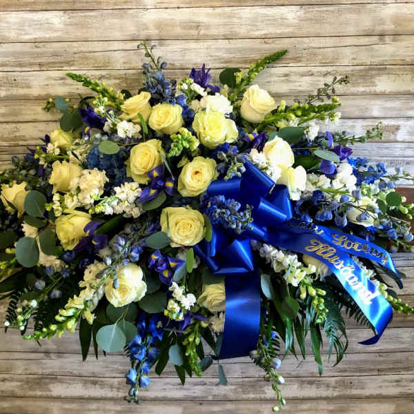 Blue and yellow floral spray with ribbon on a wooden background