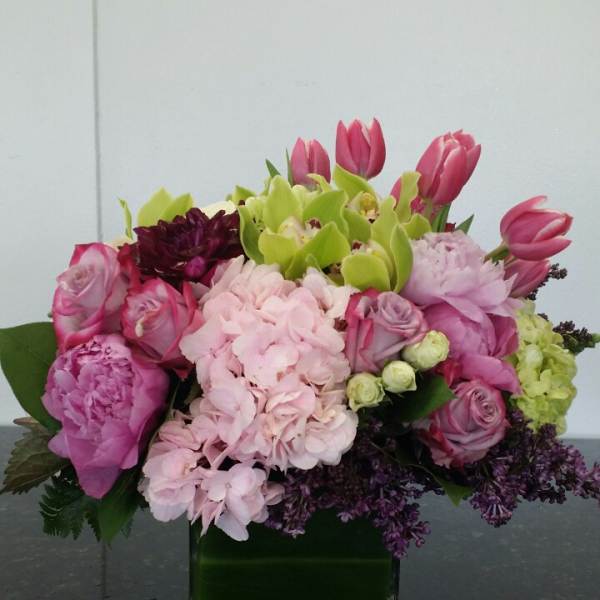 Pink and green mixed flower arrangement in a square glass vase