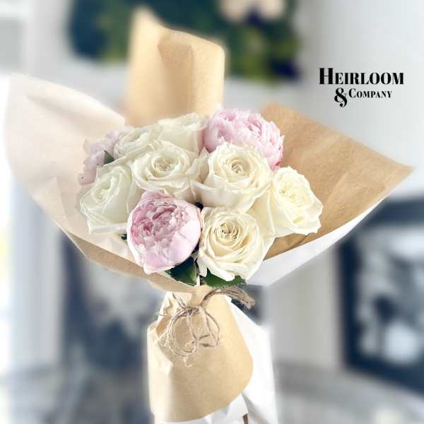 Bouquet of white and pale pink roses wrapped in brown paper