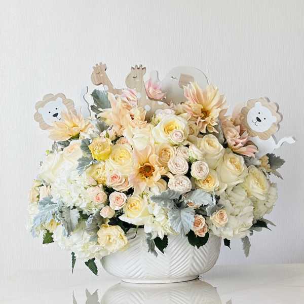 Pastel floral arrangement in a white bowl with animal picks