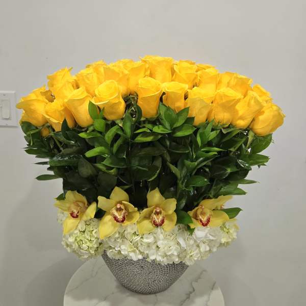 Yellow roses and yellow orchids in a silver vase with white hydrangeas
