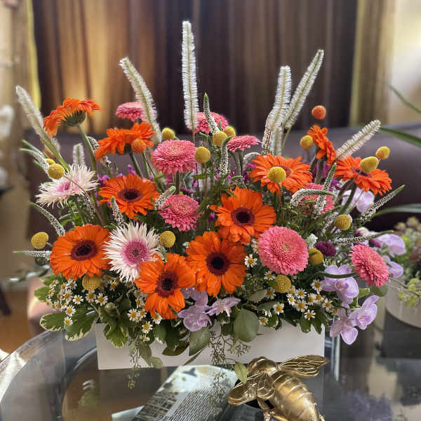 Bright mixed flower arrangement in a white rectangular container