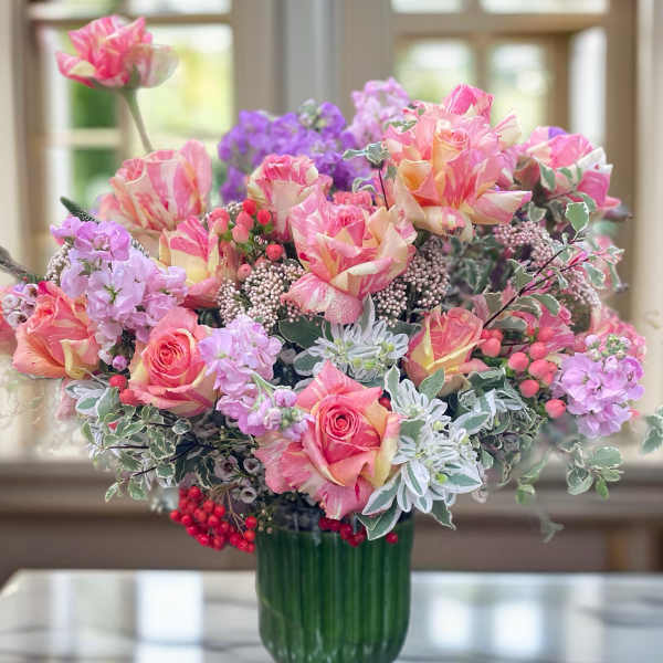 Pink and peach roses arranged in a green glass vase