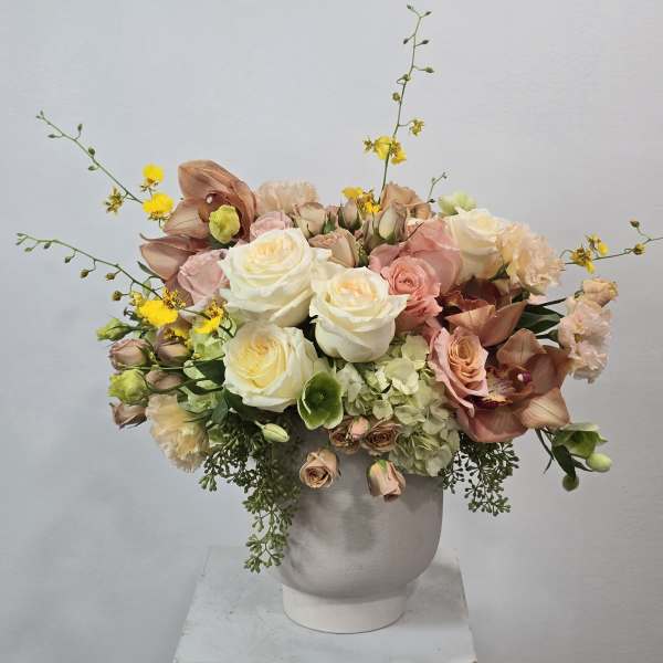 Bouquet of white and blush roses with peach orchids in a white vase