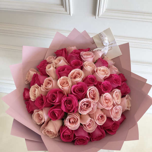 Bouquet of pink and hot pink roses wrapped in blush paper