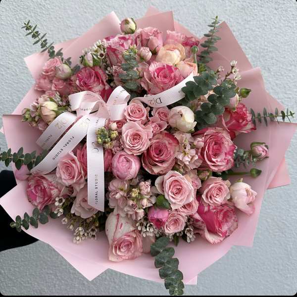 Pink rose bouquet wrapped in pale pink paper with ribbon