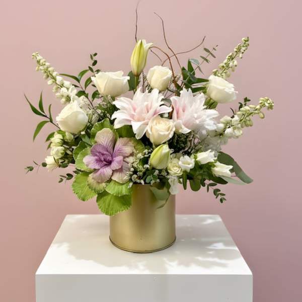 Mixed white and pale pink flowers arranged in a gold cylindrical vase