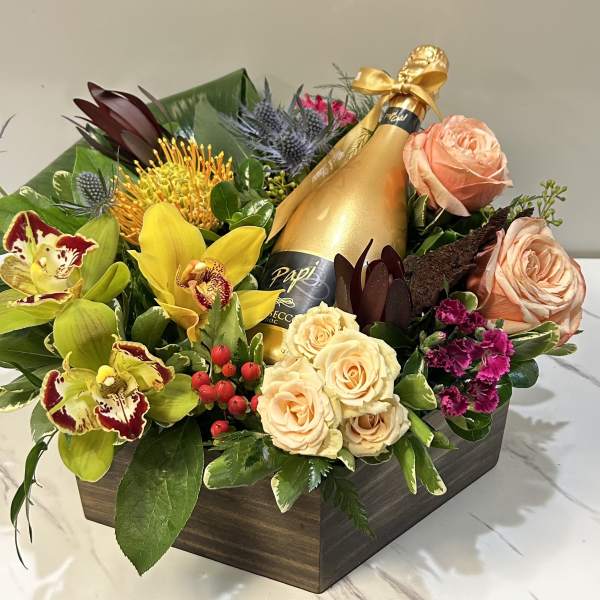 Mixed floral arrangement with a champagne bottle in a wooden box