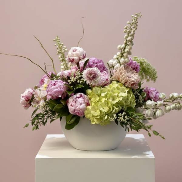Pink and white floral arrangement in a white bowl vase