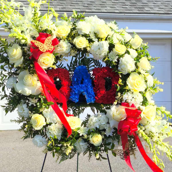 Large floral wreath on an easel with red, white, and blue lettering