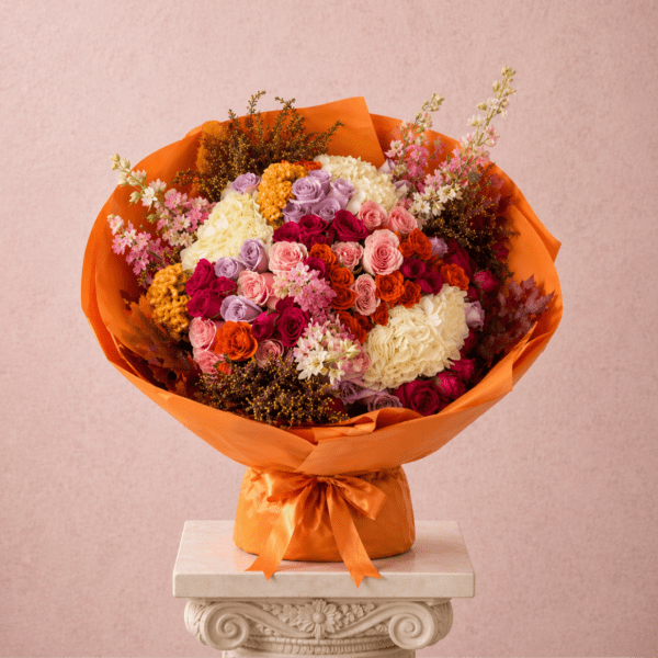 Mixed bouquet of colorful roses wrapped in bright orange paper