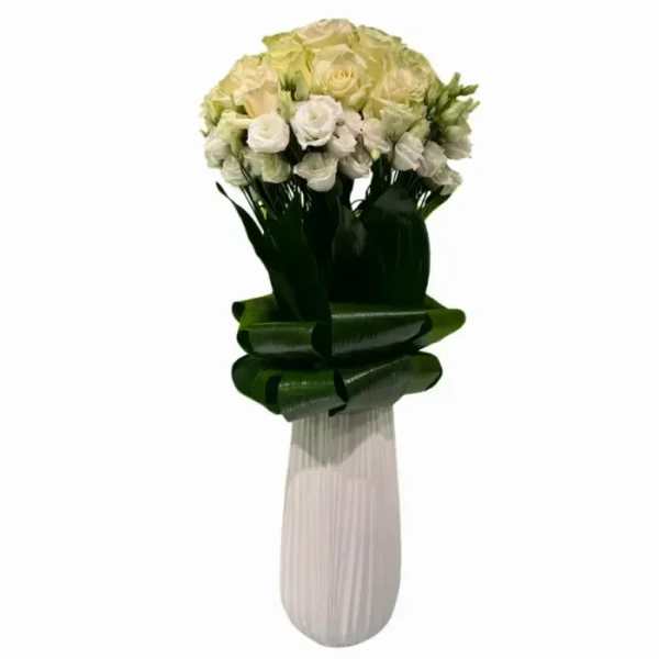 Bouquet of white and pale yellow roses in a tall wrapped vase
