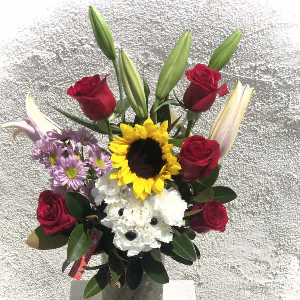 Bouquet of red roses, lilies, sunflowers, and white flowers in a vase