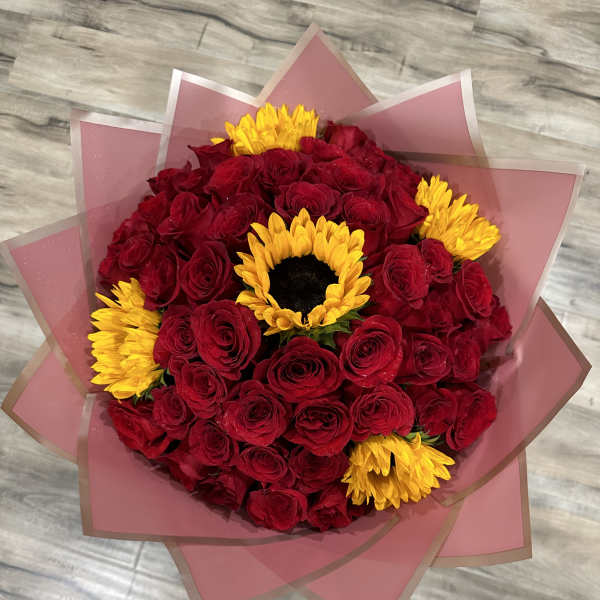 Bouquet of red roses with yellow sunflowers wrapped in pink paper