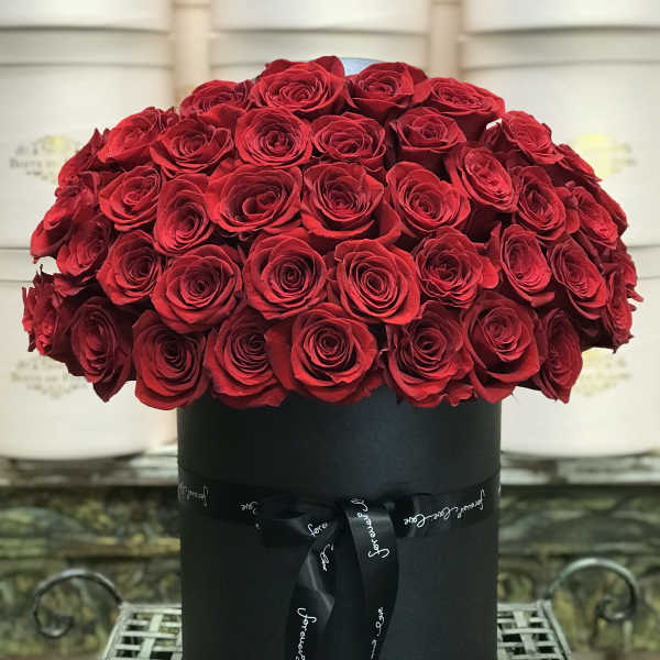 Red roses arranged in a black round box with a ribbon