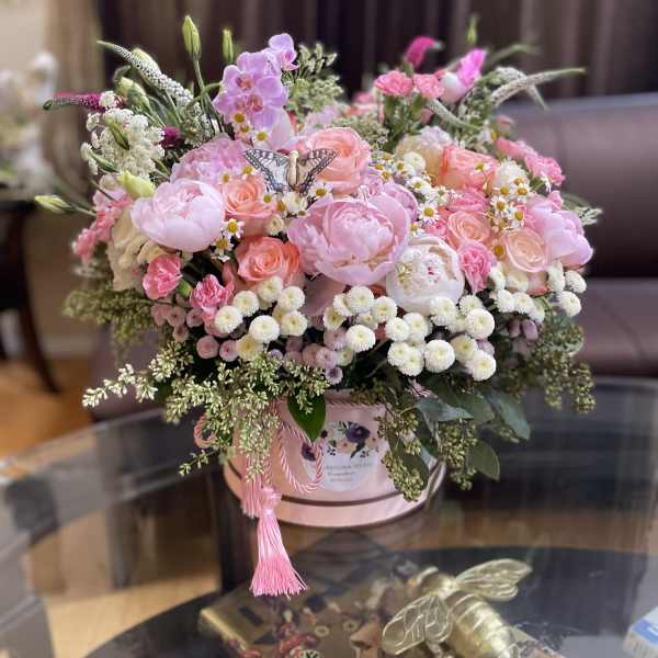 Pink mixed flower arrangement in a round hatbox with a tassel