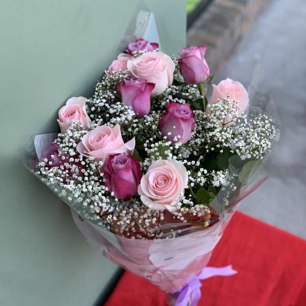 Bouquet of pink roses with white baby's breath in clear wrap