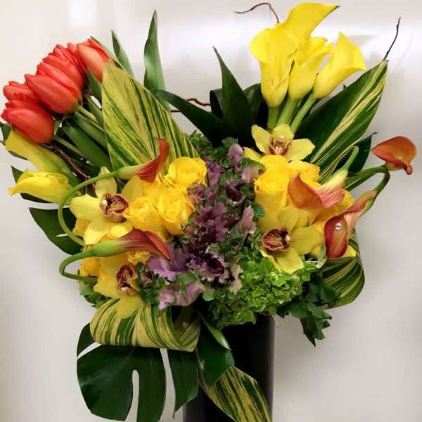 Colorful bouquet with tulips, calla lilies, orchids, and roses in a black vase