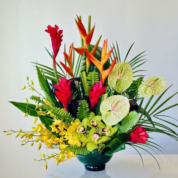 Tropical flower arrangement in a dark vase with red, orange, yellow, and green blooms