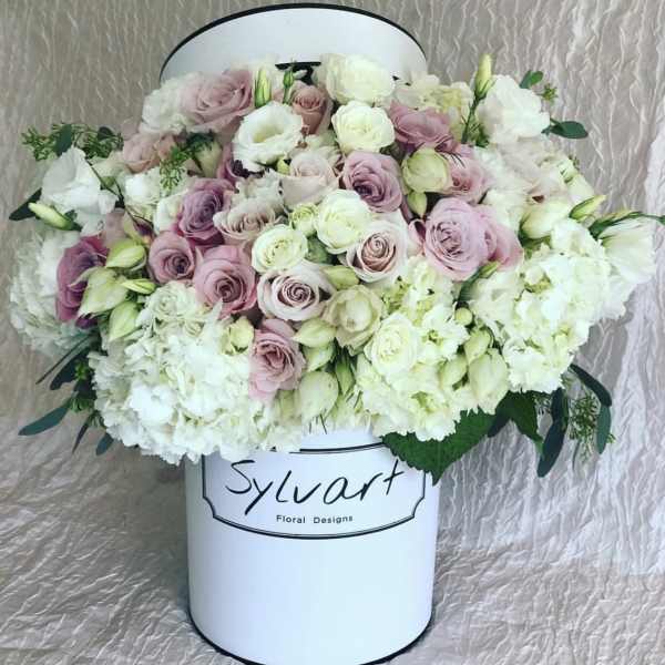 Pink and white roses arranged in a white hat box
