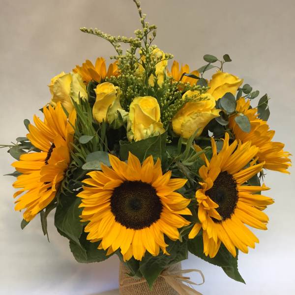 Bouquet of yellow roses and sunflowers in a burlap-wrapped vase